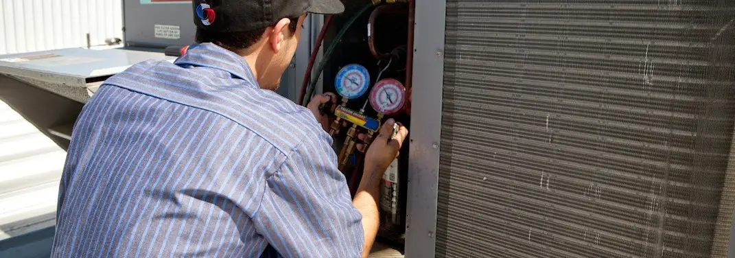 HVAC technician servicing a condenser unit in Brockport